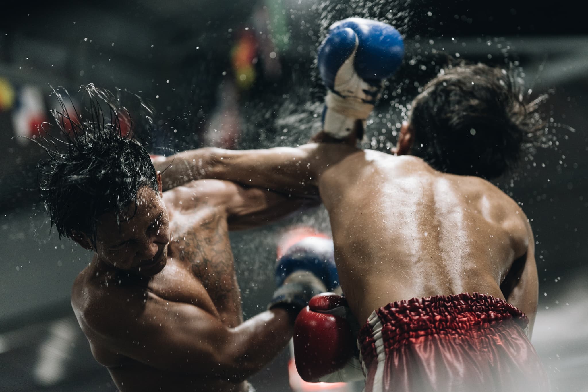 Two muscular boxers clash in the ring, sweat spraying from a powerful, high-impact punch.