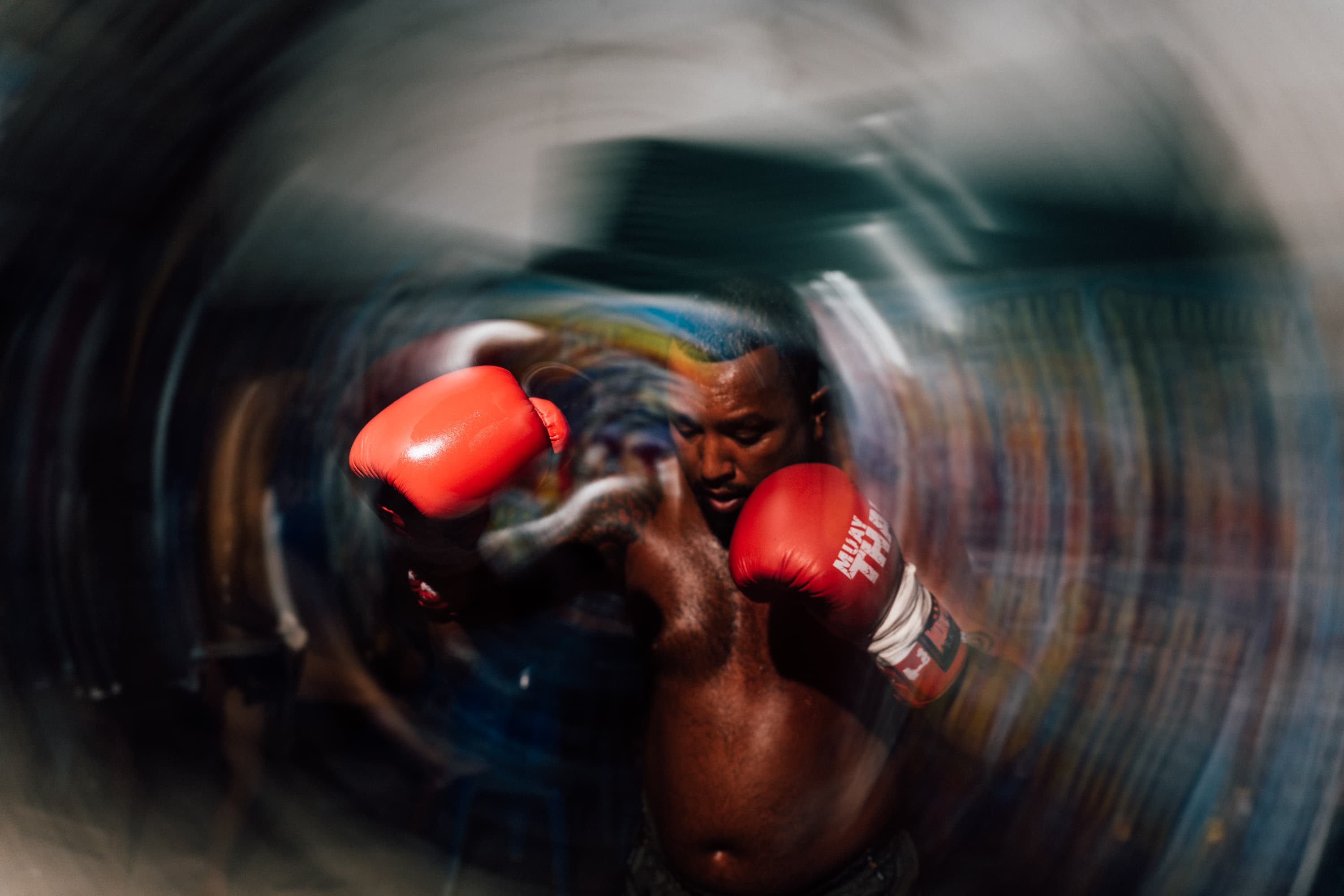 Shirtless boxer wearing red gloves throwing a punch with intense radial motion blur effect.