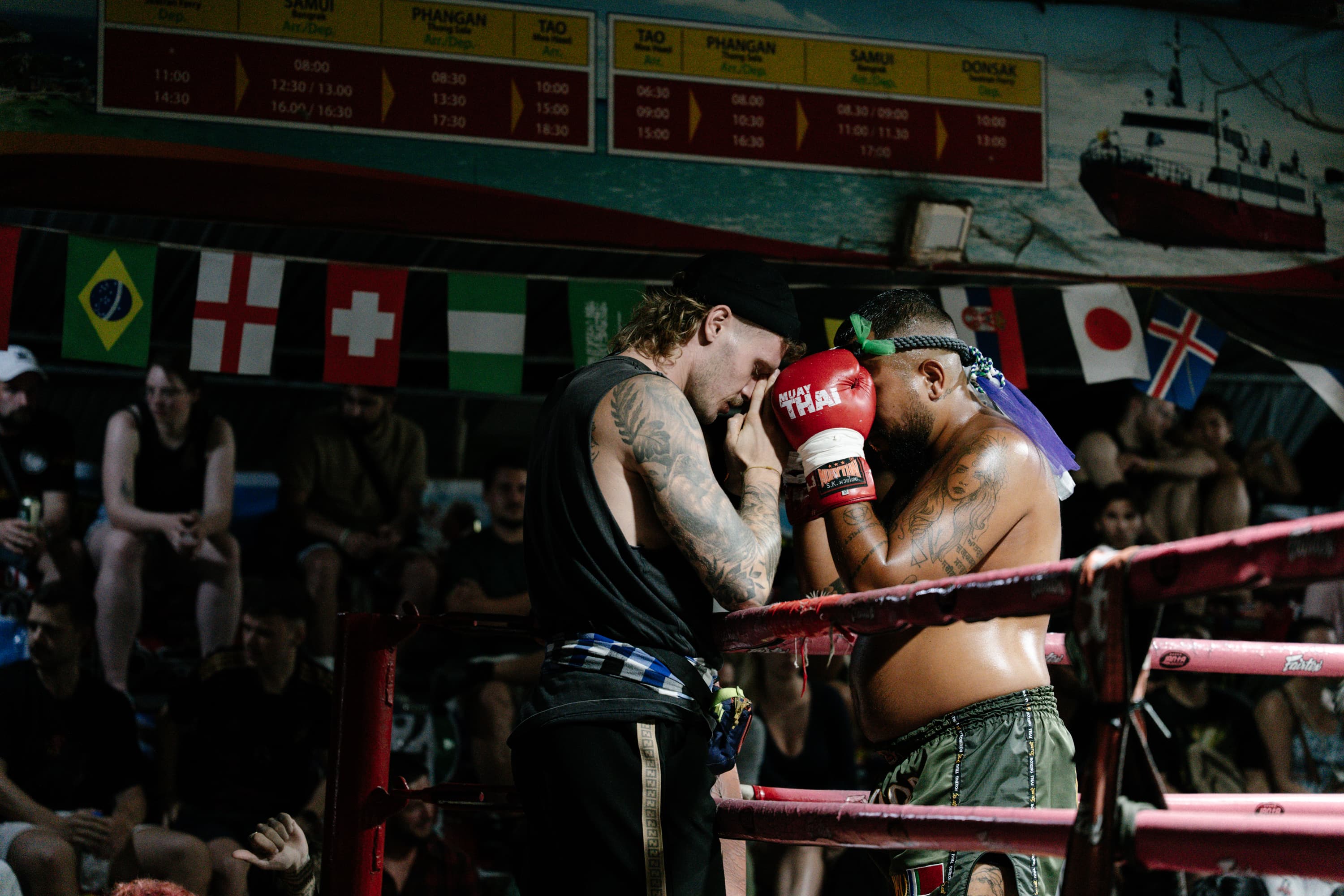 A Muay Thai fighter and trainer touch foreheads during a respectful pre-fight ritual.
